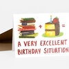 A greeting card shows a stack of books plus a slice of birthday cake with a candle and strawberry, with the text "A VERY EXCELLENT BIRTHDAY SITUATION."