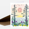 A folded greeting card with the text "JOYFUL BIRTHDAY WISHES" and an illustration of tall trees, birds, flowers, and two seals in the water.