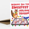 A folded holiday greeting card with red hand-lettered text reading "Wishing you the sweetest holiday season" and a cartoon chipmunk holding candy above a tray of decorated cookies.