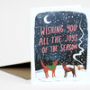 A folded greeting card with a snowy nighttime illustration of two dogs wearing scarves, a crescent moon, and the text "WISHING YOU ALL THE JOYS OF THE SEASON."