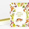 A folded birthday notecard with a watercolor armadillo illustration and cactus border, printed with the words "HAPPY BIRTHDAY DUDE" on the front.