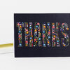 A black greeting card with the word “THANK YOU” in large floral-patterned block letters.