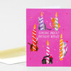 A folded birthday card with a bright pink front showing cats wearing party hats around striped birthday candles and the text "SENDING BRIGHT BIRTHDAY WISHES".