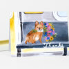 A folded greeting card features an illustration of a small brown dog holding a colorful bouquet, with the word “Thanks” written on the front.