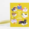 A yellow birthday greeting card with illustrated cats reading books and the text "One year older, wiser, cuter. Happy Birthday!"