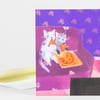 A folded greeting card shows two illustrated cats holding slices of pizza on a purple couch against a purple wall with flower motifs.