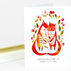 An open white greeting card shows a watercolor-style illustration of two foxes with leaves and the printed text "CONGRATULATIONS ON YOUR LITTLE ONE."