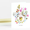 A folded white greeting card with a watercolor floral wreath around a swaddled baby illustration and the text "OH BABY!" on the front.