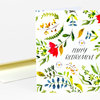 A folded greeting card with a botanical leaf-and-flower pattern and the words "HAPPY RETIREMENT" on the front, shown with an envelope.