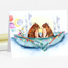A folded notecard with a watercolor illustration of two bears in a boat holding signs that read "just" and "married," with balloons and bunting around them.
