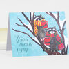 A folded holiday notecard with an illustration of two raccoons in winter scarves sitting on tree branches, with the text "Warm Holiday Wishes" on the front.