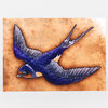 A postcard featuring a painted swallow in flight with deep blue body, gray wings, and an orange throat on a tan mottled background.