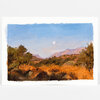 A postcard-sized art print of a painted landscape with blue sky, a small moon, distant mountains, and orange-brown grasses and trees in the foreground.