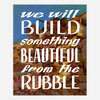 An art print with the text “we will BUILD something BEAUTIFUL from the RUBBLE” in large white lettering over a painted abstract landscape-like background.