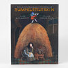 A paperback book cover titled "RUMPELSTILTSKIN" with the text "Retold by MAC BARNETT" and "Illustrated by CARSON ELLIS," showing an illustrated figure standing on a large mound of straw above a seated woman beside a spinning wheel.