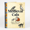 A hardcover book titled "Medieval Cats" with the subtitle "Claws, Paws, and Kitties of Yore," featuring several illustrated cats on the cover and a patterned spine that reads "Medieval Cats."