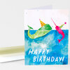 A folded birthday card with watercolor-style whales wearing party hats above the white text "HAPPY BIRTHDAY!".