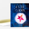 A folded greeting card with a blue cover that reads "A STAR IS BORN" above a pink and orange star illustration surrounded by small white star marks.
