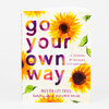 A journal with a sunflower-patterned cover that reads “go your own way,” with smaller text reading “A JOURNAL for BUILDING SELF-CONFIDENCE” and “MEERA LEE PATEL.”