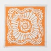 An orange and white square bandana with a floral and pollinator-style graphic print and a thin double border.