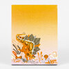 A notepad with a yellow gradient cover featuring a stylized orange and gray stegosaurus illustration with plants along the bottom edge.
