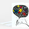A folded greeting card shows a black-and-white bird illustration with a large stylized speech bubble filled with colorful flowers and vine-like patterns, with a matching envelope partially visible behind it.