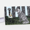 A folded greeting card shows a black-and-white illustrated girl in a floral dress facing a seated wolf in a forest with dark tree trunks and green grass.
