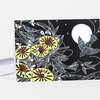 A folded greeting card with a black cover showing white line-art birds, bees, flowers, and a large white moon with yellow and red flower accents.
