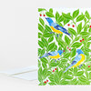 A folded greeting card with a pattern of three blue-and-yellow birds among bright green leaves and small red berries.