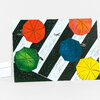 A folded greeting card featuring five colorful umbrellas in orange, green, blue, yellow, and coral on diagonal black-and-white striped pattern.
