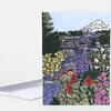 A folded greeting card featuring a colorful illustrated landscape with a river, snow-capped mountain, evergreen trees, and dense wildflowers.