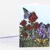 A folded greeting card with a colorful illustrated meadow scene of red and purple wildflowers, butterflies, and mountains, with no visible text.