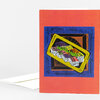 A folded greeting card with a coral-red cover featuring a colorful abstract linocut-style fish on a tray-like shape.