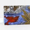 A folded greeting card or art card featuring a colorful illustrated scene of red fish swimming in blue water with a forest, a river, and a large fern leaf.
