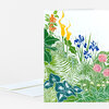 A folded greeting card with a colorful botanical garden illustration featuring green leaves, blue flowers, pink blossoms, and tall yellow and orange blooms.