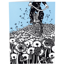 A folded greeting card with a black-and-white illustration of a person riding a bicycle through a field of flowers against a light blue sky.