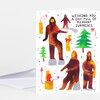 A folded greeting card with a colorful illustrated cover showing several stylized bear-like figures, small trees, and the printed text "WISHING YOU A DAY FULL OF PLEASANT SURPRISES."