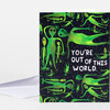 A folded greeting card with a black cover patterned with green alien figures and white text that reads "YOU'RE OUT OF THIS WORLD."