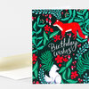A folded greeting card with a dark floral pattern, a red fox and a white fox illustration, and the text "Birthday wishes!" on the front.