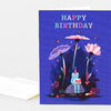 A folded birthday greeting card with a blue cover that reads "HAPPY BIRTHDAY" above an illustration of a frog wearing a party hat and holding a gift among tall flowers and small butterflies.