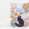 A folded greeting card with a light blue floral design, a black cat illustration, and the text "HAVE A Purrrrrfect BIRTHDAY!" on the front.
