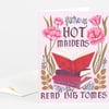 A folded greeting card with a pink cover featuring the text "HOT MAIDENS READ BIG TOMES," an illustration of stacked books with an open red book on top, and floral decorations.