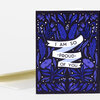 A folded greeting card with a dark floral illustration and a white ribbon reading "I AM SO PROUD OF YOU."