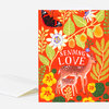 A folded greeting card with a bright red floral and butterfly illustration, two deer, and the words "SENDING LOVE" in white text on the front.