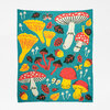 A turquoise knit blanket patterned with colorful mushrooms, leaves, acorns, and small butterflies.