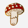 A mushroom-shaped enamel pin with a red cap, white spots, white gills, and a cream-colored stem outlined in gold.