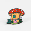 A mushroom house enamel pin with a red cap covered in white spots, a tan stem, teal windows, a pink door, and small flowers and leaves around the base.