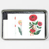 A rectangular metal tin containing folded temporary tattoo sheets decorated with illustrated red flowers, green leaves, and a small flower fairy figure.