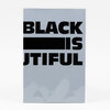 A rectangular sheet or card with large bold black text reading "BLACK [solid black bar] IS JTIFUL" on a light gray background.
