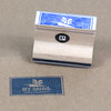 A small rectangular rubber stamp with a wooden block, blue rubber face, a black oval logo with a white "P" on the side, and the stamped text "BY SNAIL / PAR L'ESCARGOT" visible on the surface below.